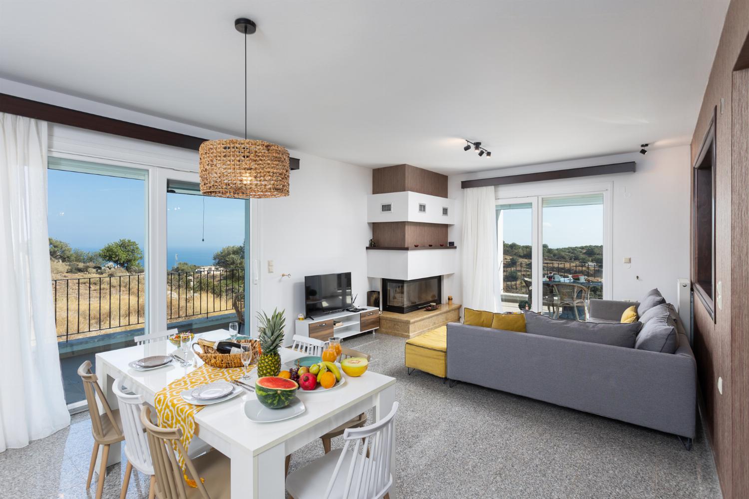 Open-plan living room with sofa, dining area, kitchen, ornamental fireplace, WiFi internet, satellite TV, and sea views