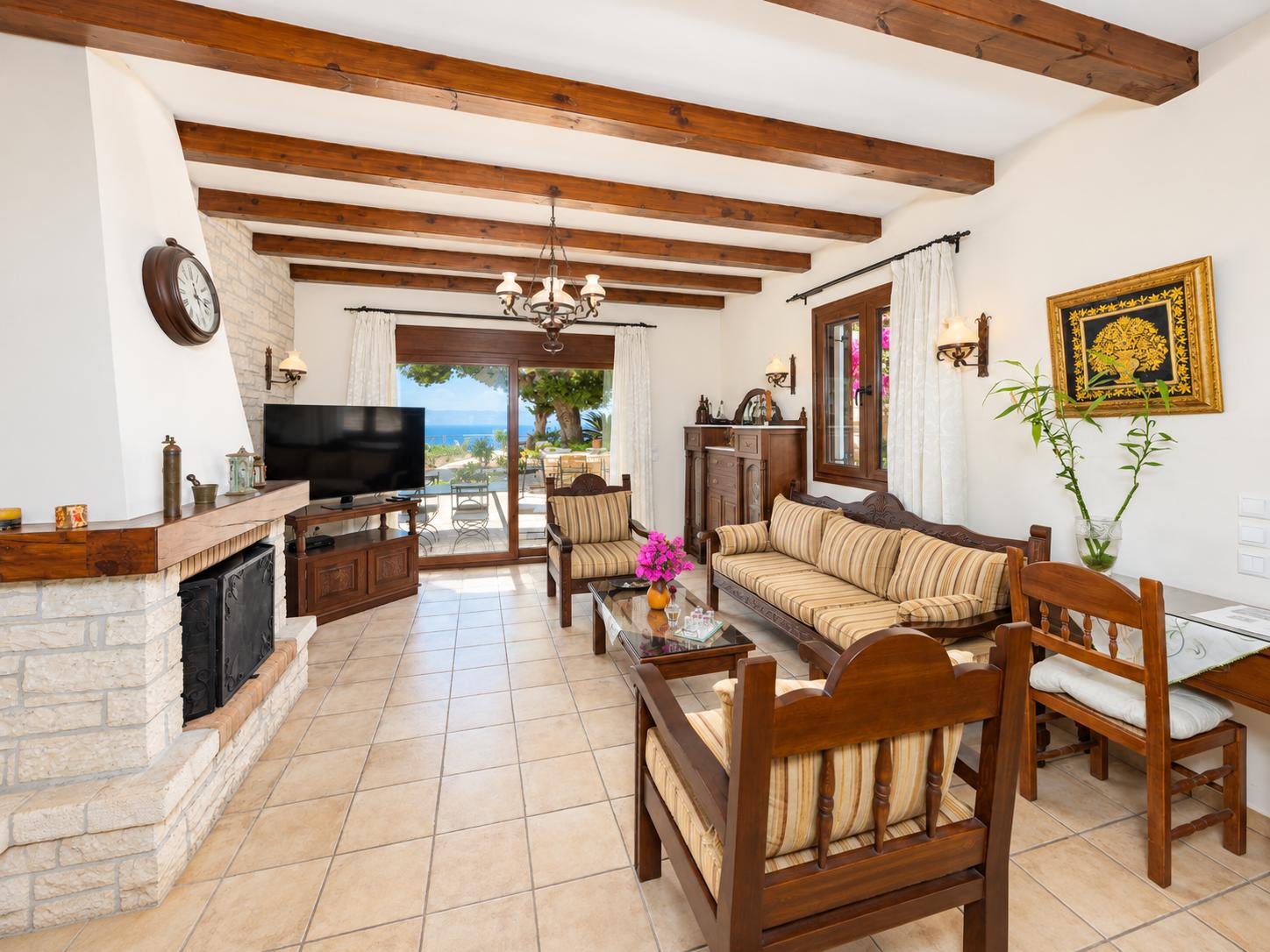Open-plan living room with sofa, dining area, kitchen, ornamental fireplace, A/C, WiFi internet, satellite TV, and sea views