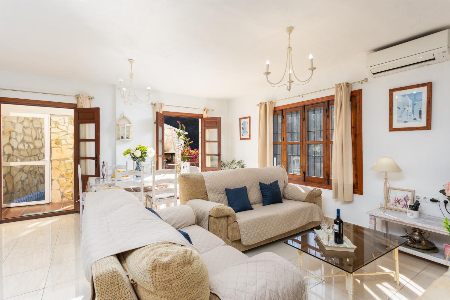 Open-plan living room with sofas, dining area, kitchen, ornamental fireplace, A/C, WiFi internet, and satellite TV