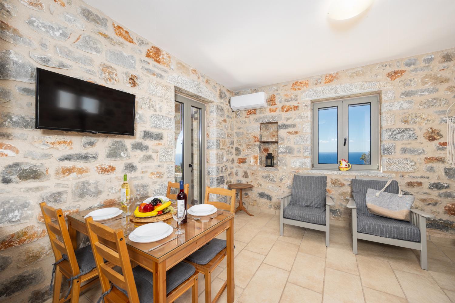 Open-plan living room with sofa, dining area, kitchen, A/C, WiFi internet, and satellite TV