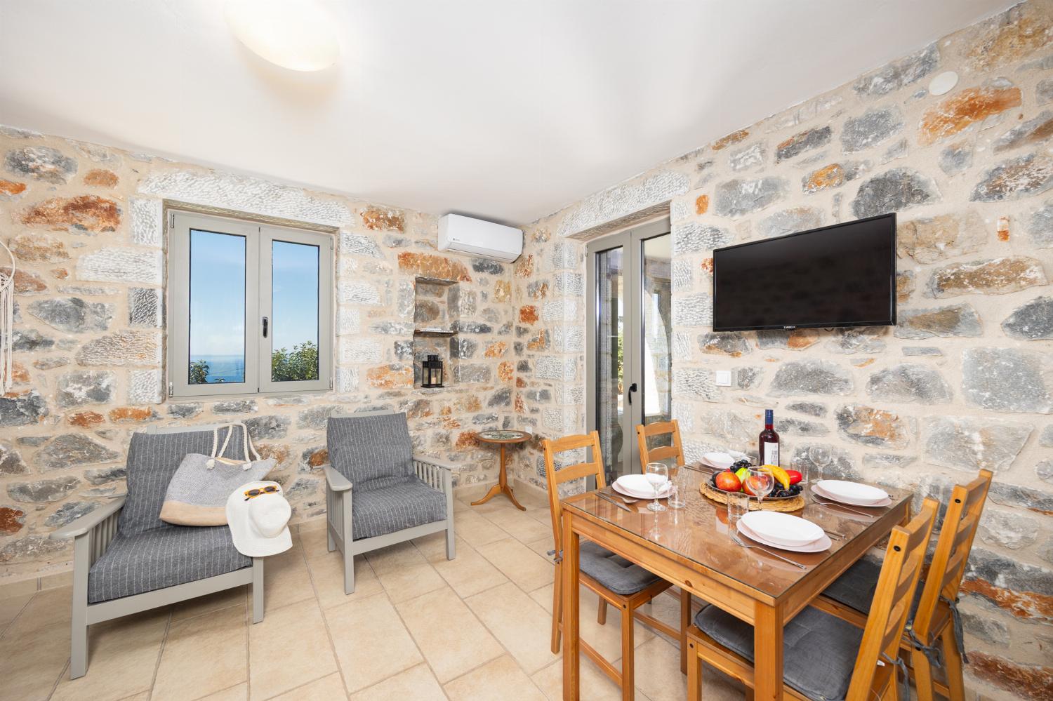 Open-plan living room with sofa, dining area, kitchen, A/C, WiFi internet, and satellite TV