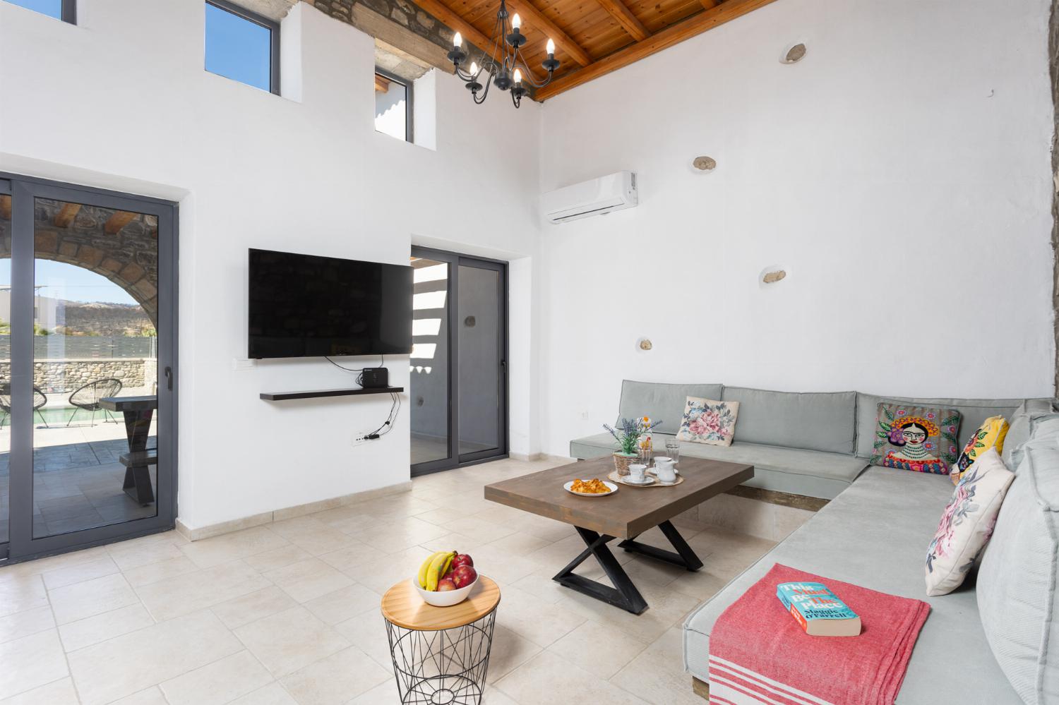 Open-plan living room with sofa, dining area, kitchen, A/C, WiFi internet, and satellite TV
