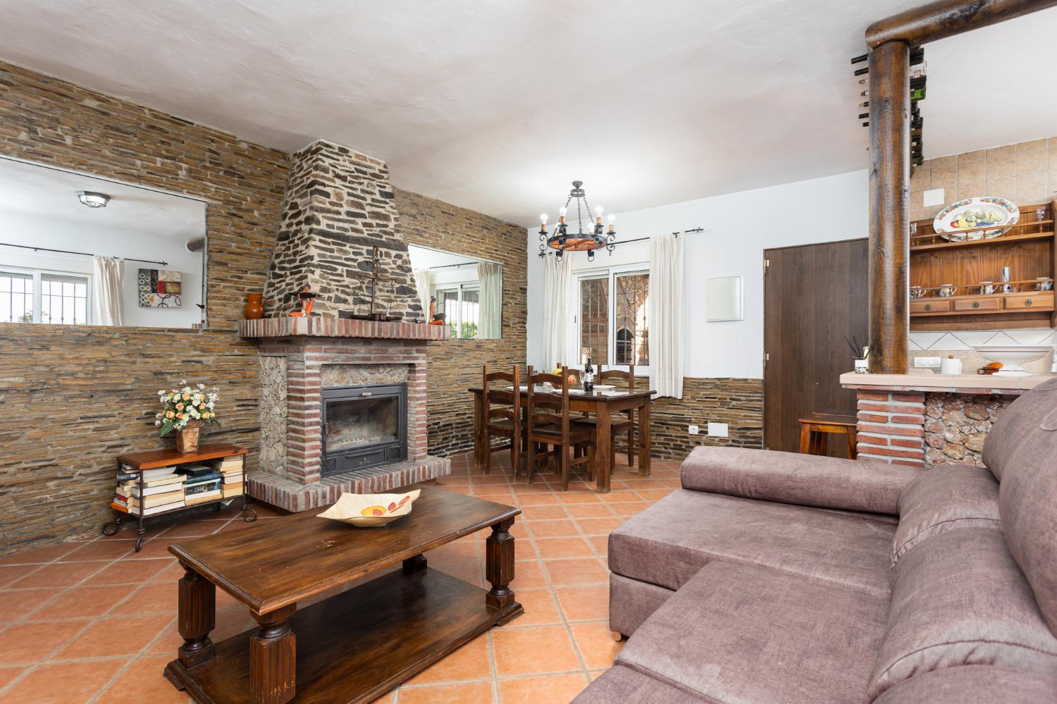 Open-plan living room with sofa, dining area, kitchen, ornamental fireplace, A/C, WiFi internet, and satellite TV
