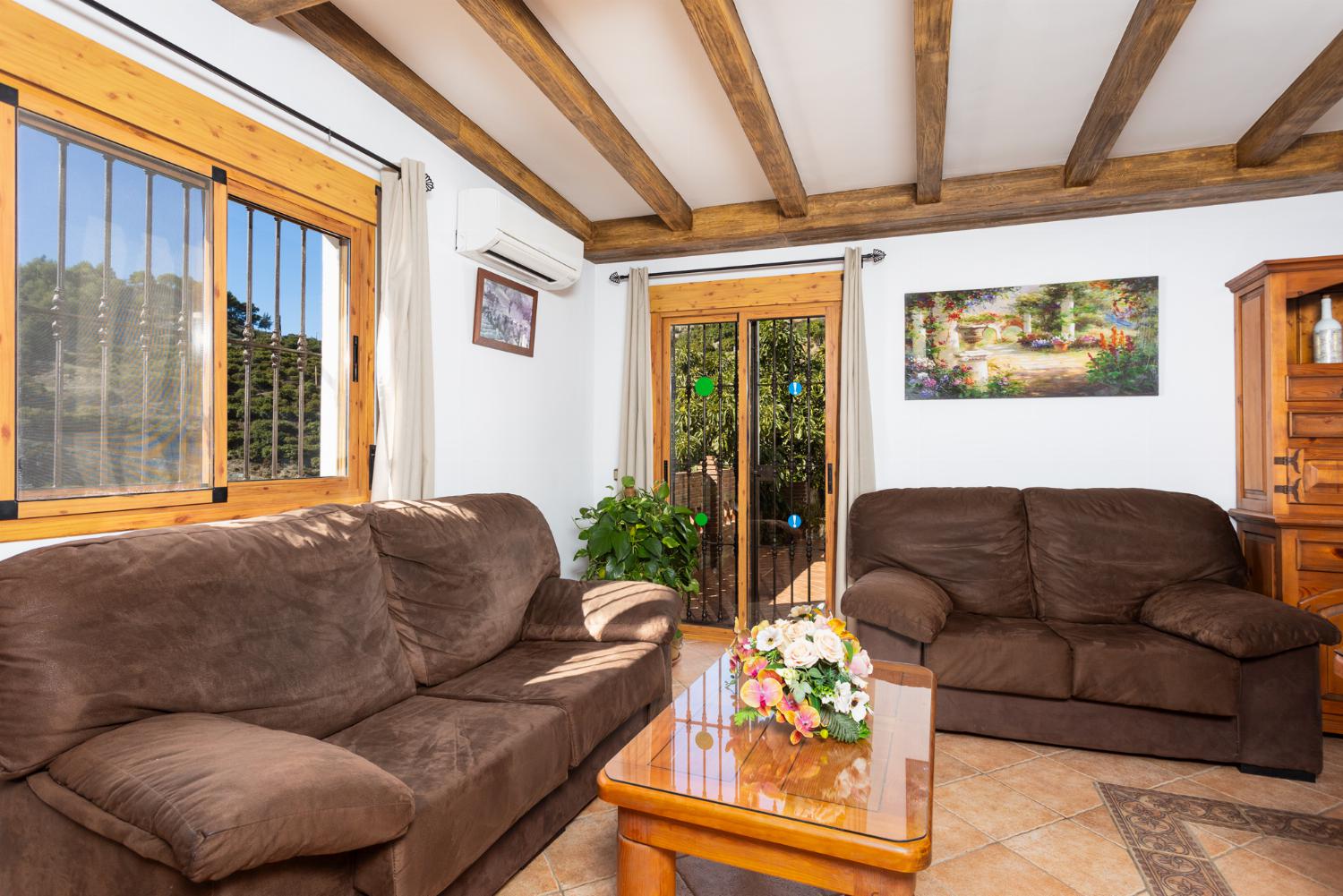 Open-plan living room with sofas, dining area, kitchen, ornamental fireplace, A/C, WiFi internet, and satellite TV