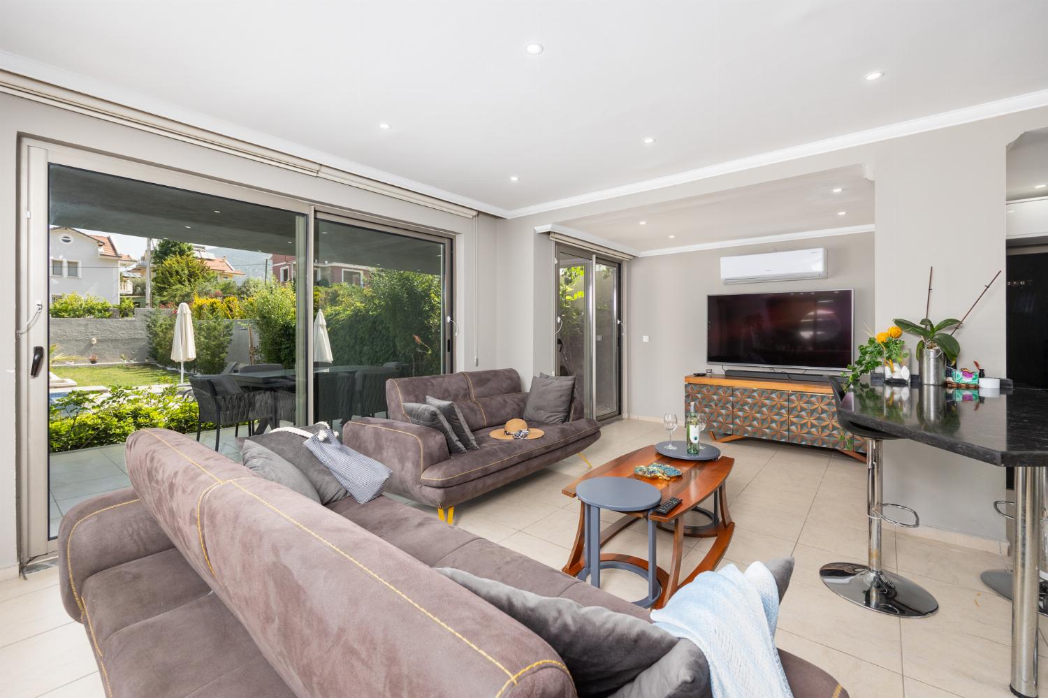 Open-plan living room with sofas, dining area, kitchen, A/C, WiFi internet, and satellite TV