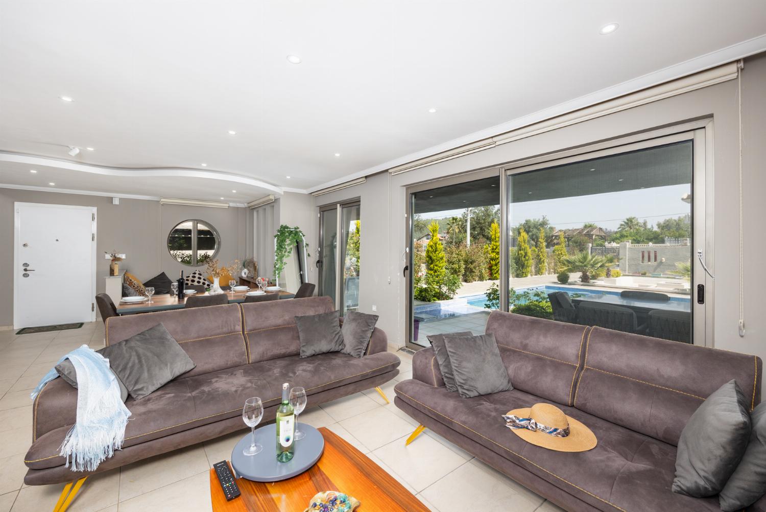 Open-plan living room with sofas, dining area, kitchen, A/C, WiFi internet, and satellite TV