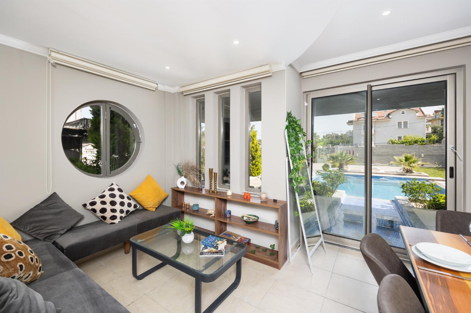 Open-plan living room with sofas, dining area, kitchen, A/C, WiFi internet, and satellite TV