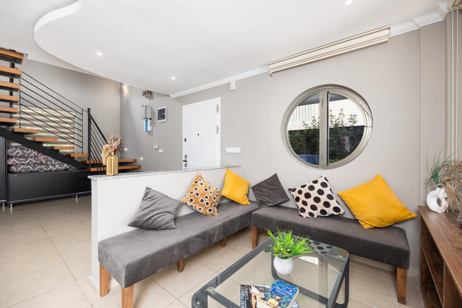 Open-plan living room with sofas, dining area, kitchen, A/C, WiFi internet, and satellite TV
