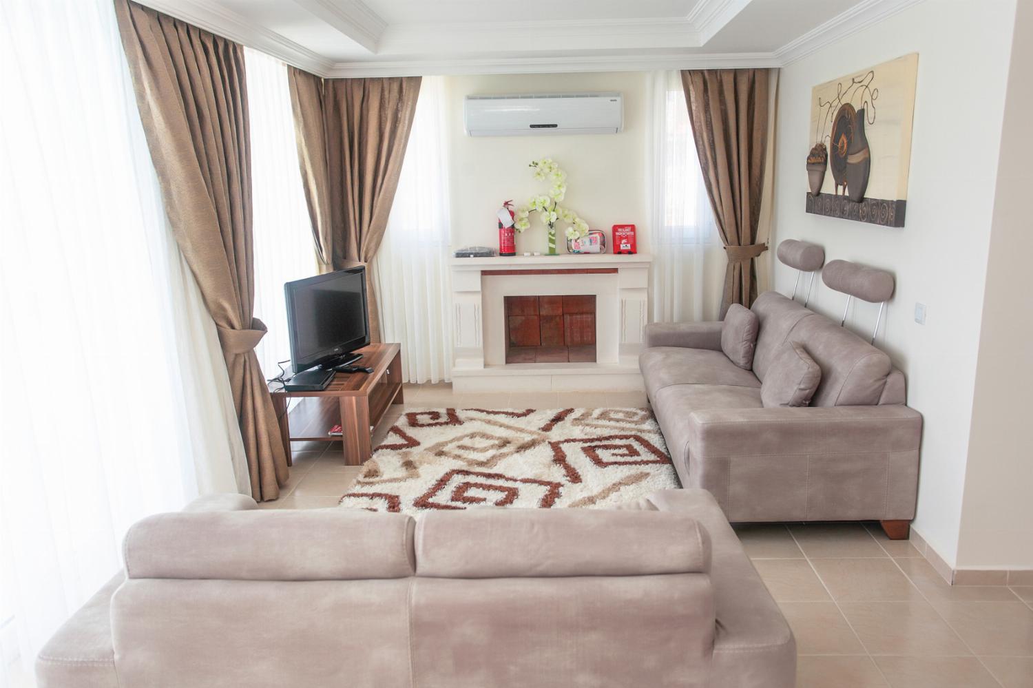 Open-plan living room with comfortable sofas, ornamental fireplace, WiFi, TV