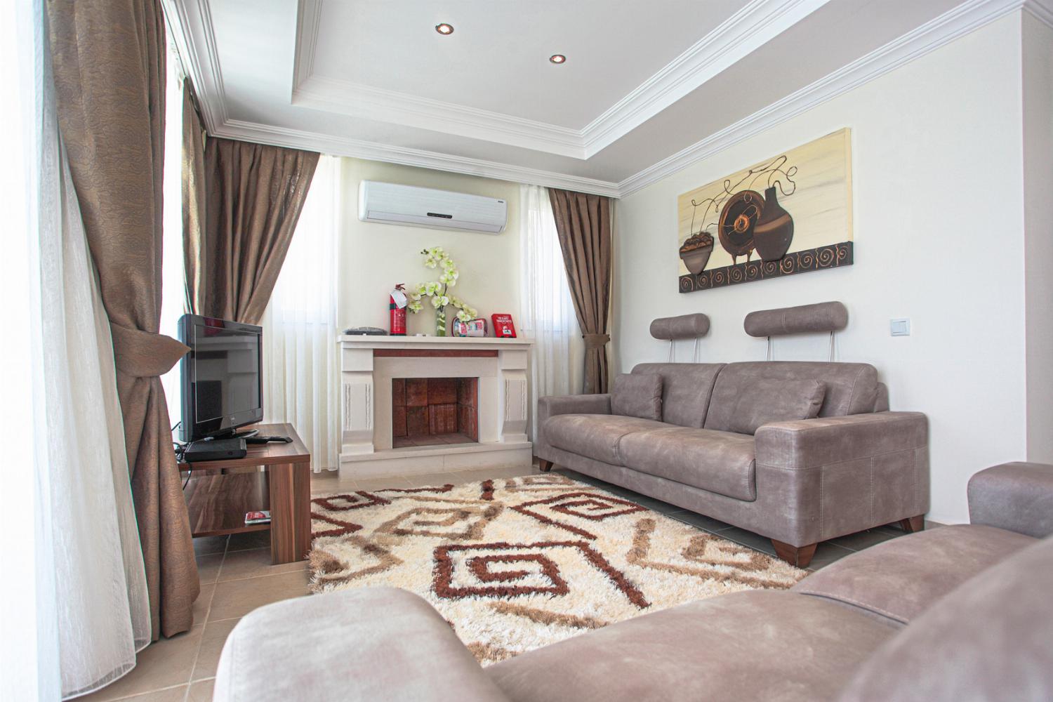 Open-plan living room with comfortable sofas, ornamental fireplace, WiFi, TV