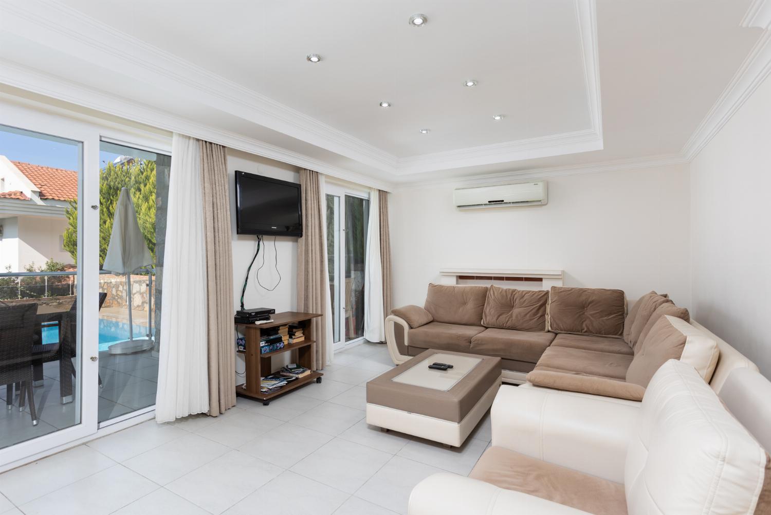 Open-plan living room with sofas, dining area, kitchen, ornamental fireplace, A/C, WiFi internet, and satellite TV