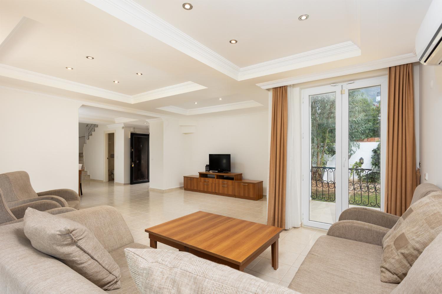 Open-plan living room with sofas, dining area, kitchen, A/C, WiFi internet, and satellite TV