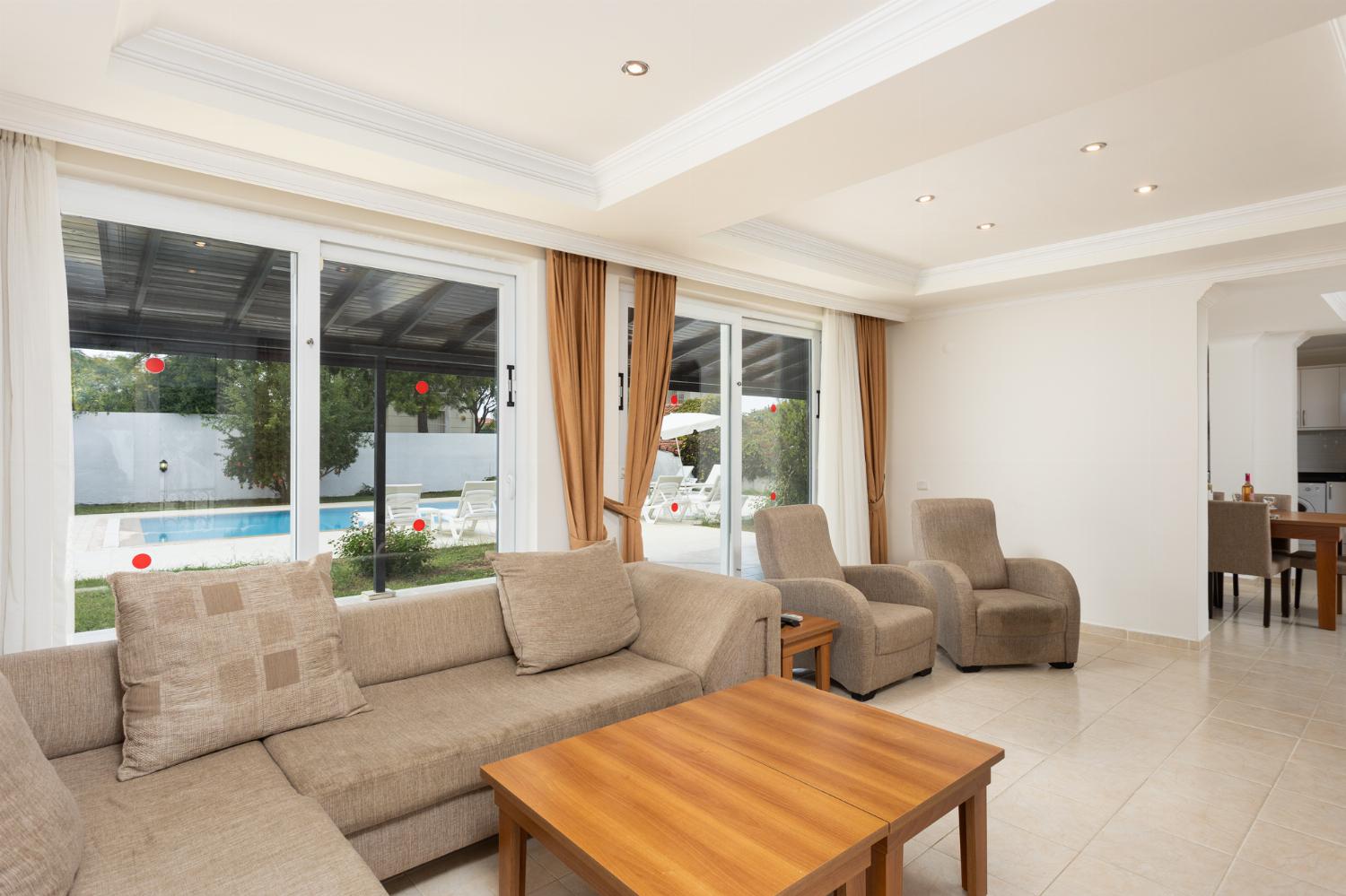 Open-plan living room with sofas, dining area, kitchen, A/C, WiFi internet, and satellite TV