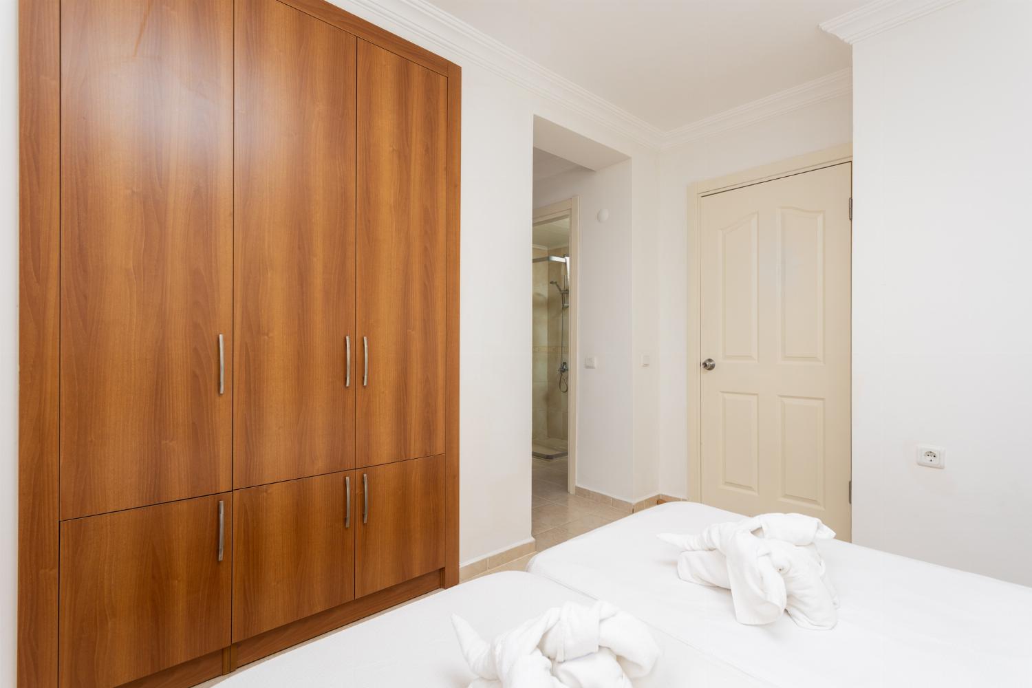 Bedroom with twin beds and single bed, en suite bathroom, and A/C