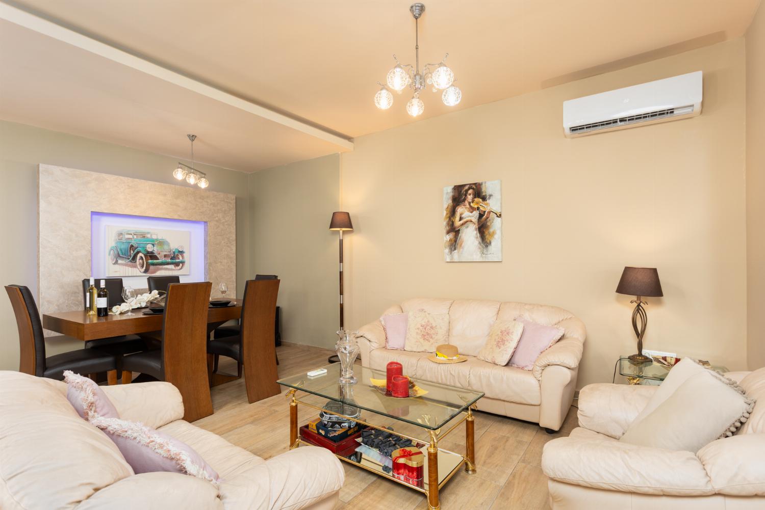 Open-plan living room with sofas, dining area, kitchen, A/C, and WiFi internet