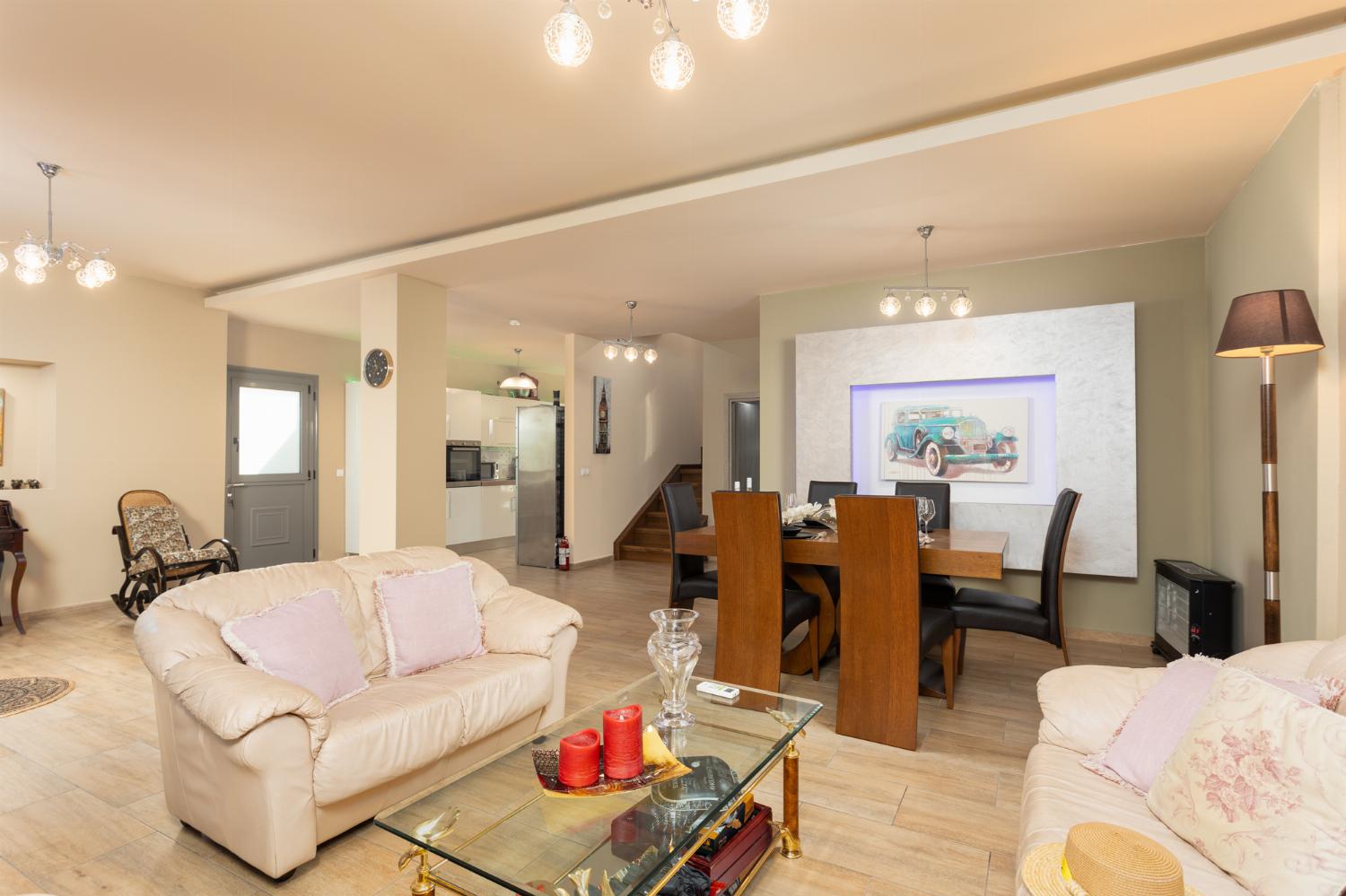 Open-plan living room with sofas, dining area, kitchen, A/C, and WiFi internet
