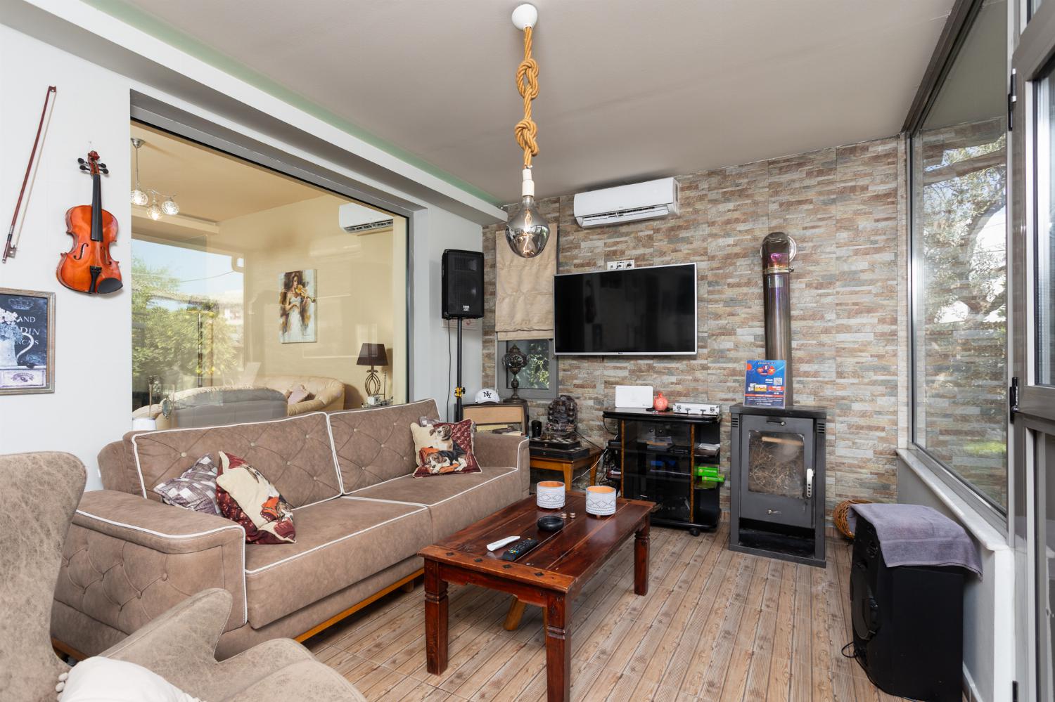 Sun room with sofa, dining area, ornamental fireplace, A/C, WiFi internet, and satellite TV