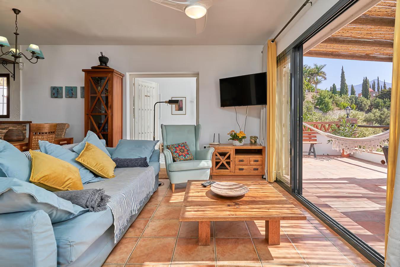 Open-plan living room with sofas, dining area, kitchen, ornamental fireplace, A/C, WiFi internet, satellite TV, and patio doors