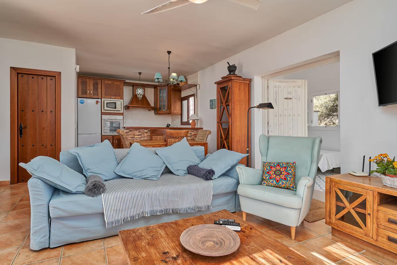 Open-plan living room with sofas, dining area, kitchen, ornamental fireplace, A/C, WiFi internet, satellite TV, and patio doors