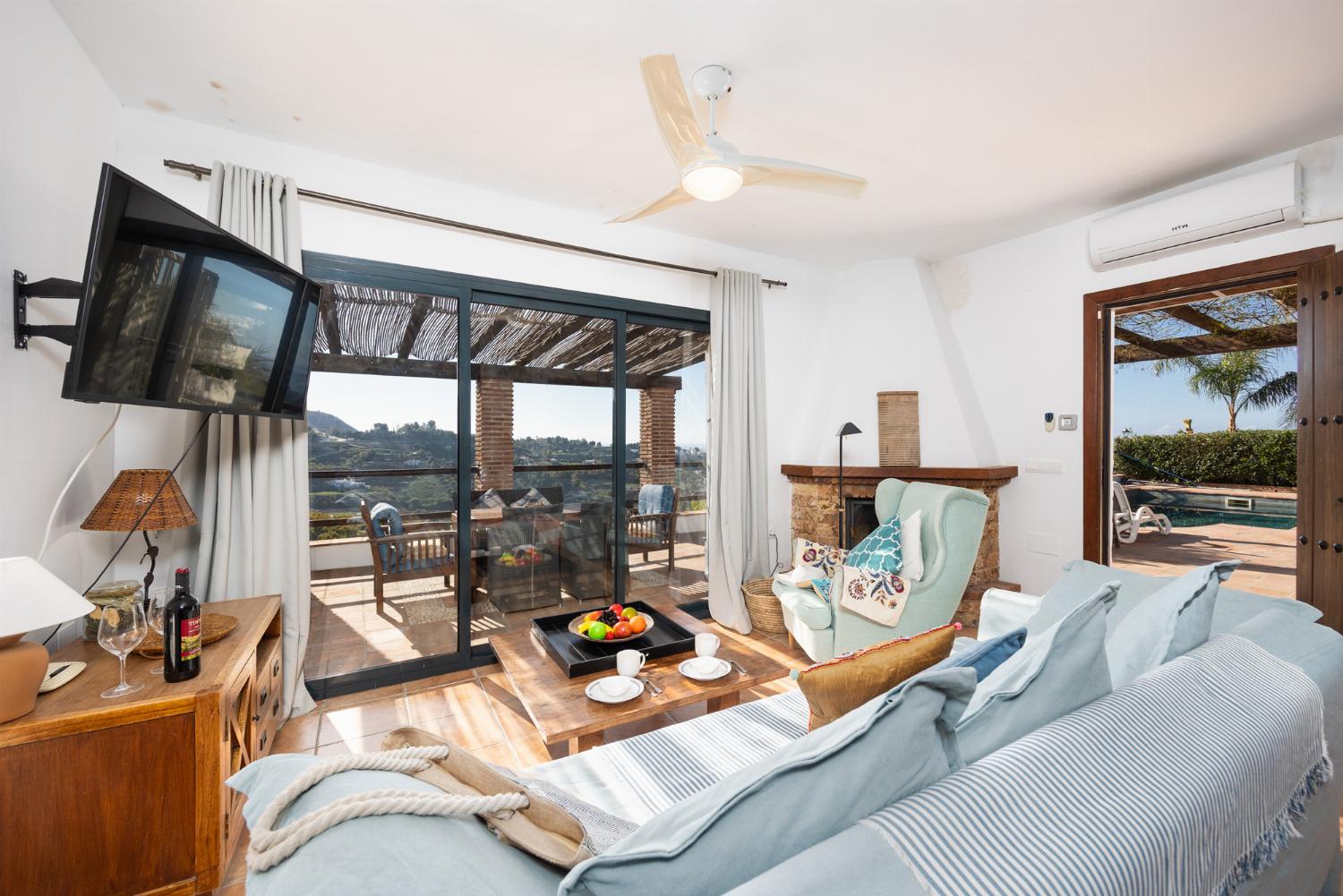 Open-plan living room with sofa, dining area, kitchen, ornamental fireplace, A/C, WiFi internet, and satellite TV