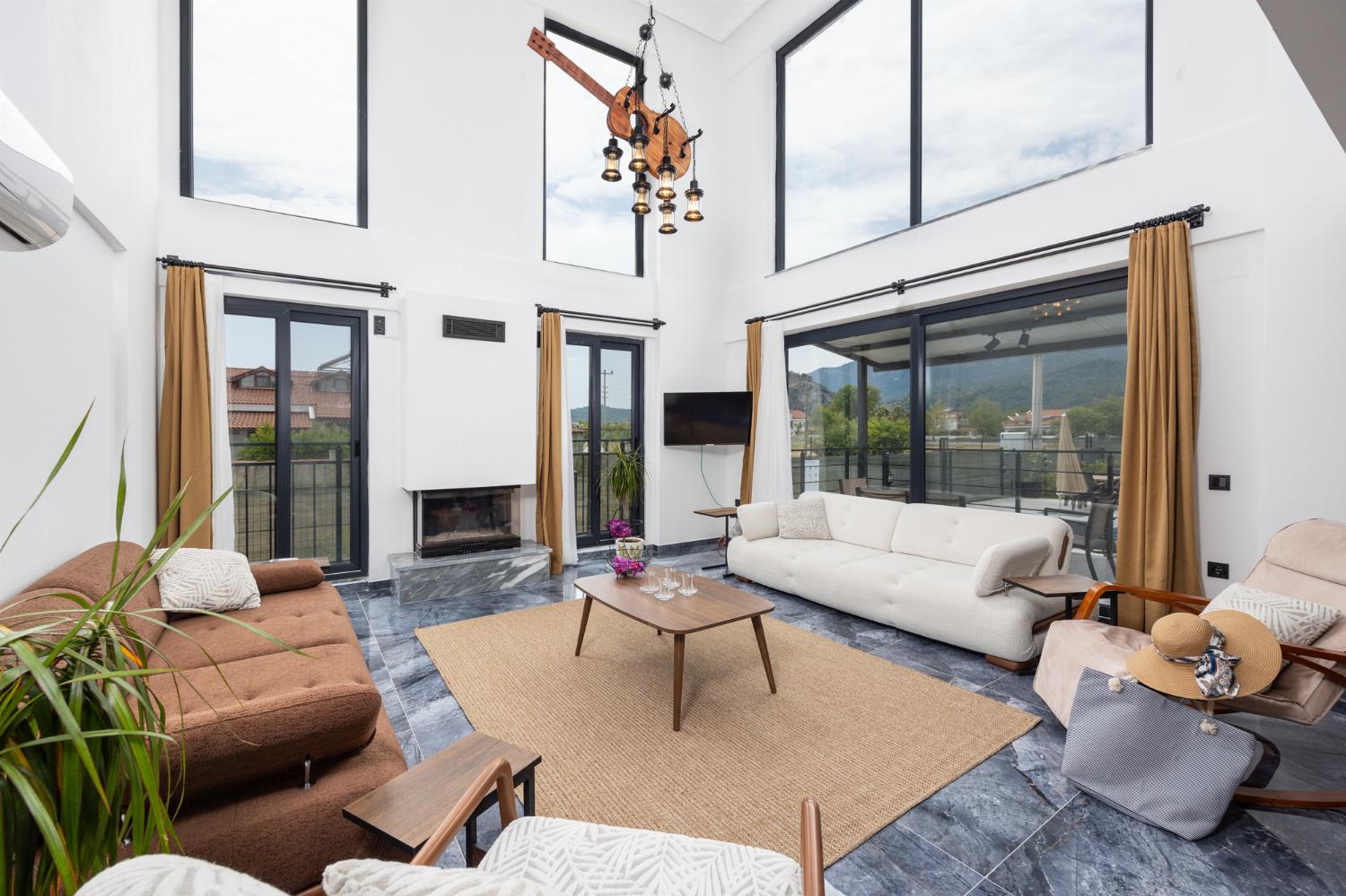 Open-plan living room with sofas, dining area, kitchen, ornamental fireplace, A/C, WiFi internet, and satellite TV