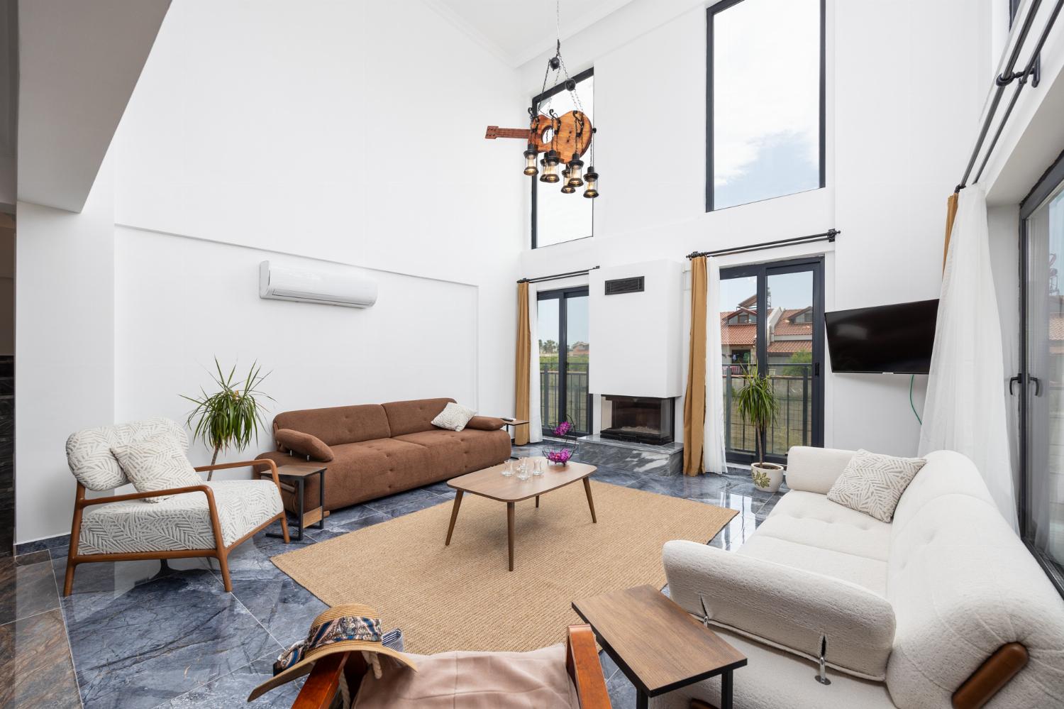Open-plan living room with sofas, dining area, kitchen, ornamental fireplace, A/C, WiFi internet, and satellite TV