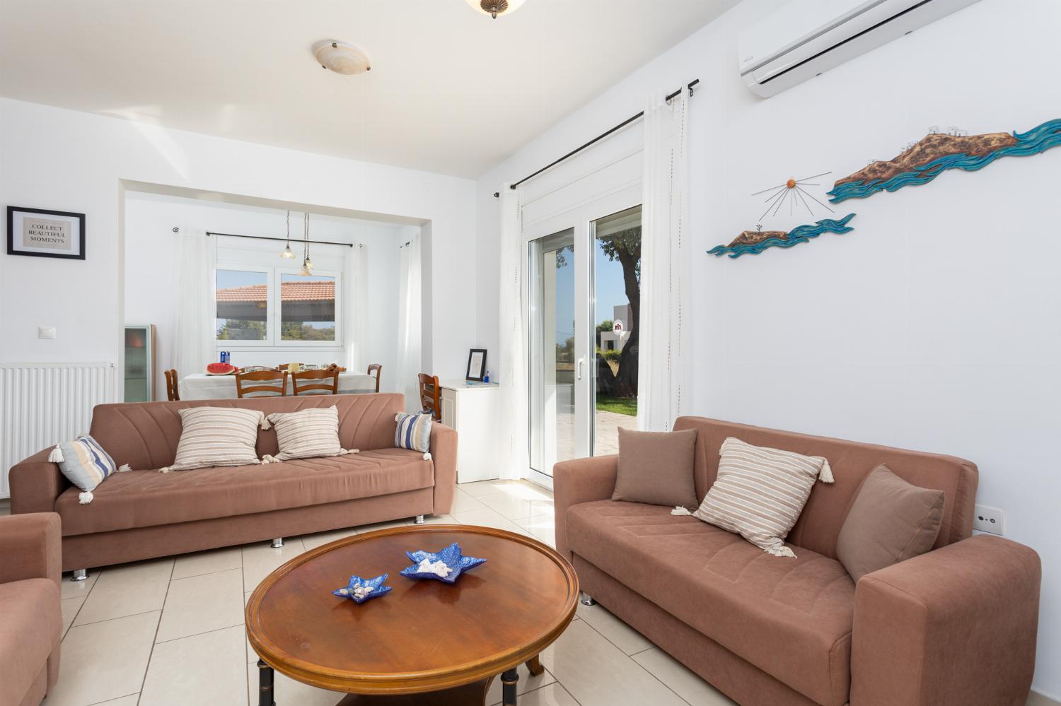 Open-plan living room with sofas, dining area, kitchen, ornamental fireplace, A/C, WiFi internet, and satellite TV