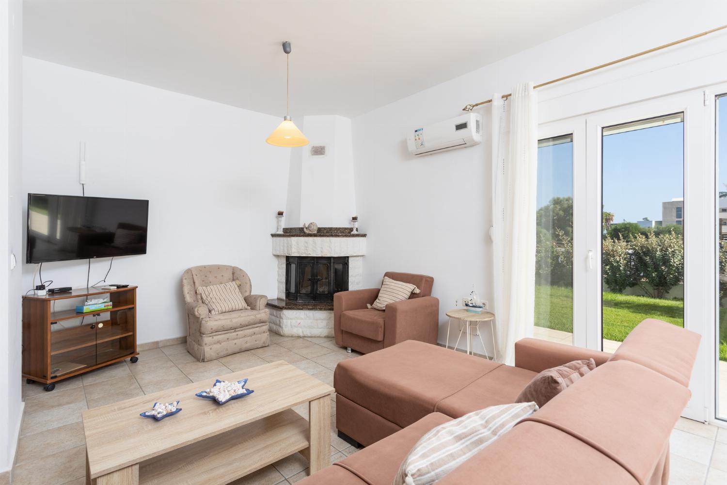 Open-plan living room with sofa, dining area, kitchen, ornamental fireplace, A/C, WiFi internet, and satellite TV