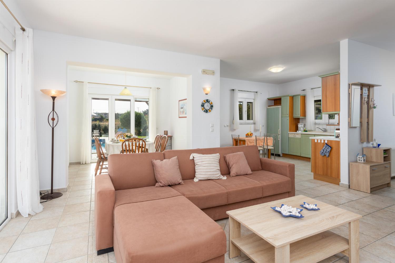 Open-plan living room with sofa, dining area, kitchen, ornamental fireplace, A/C, WiFi internet, and satellite TV