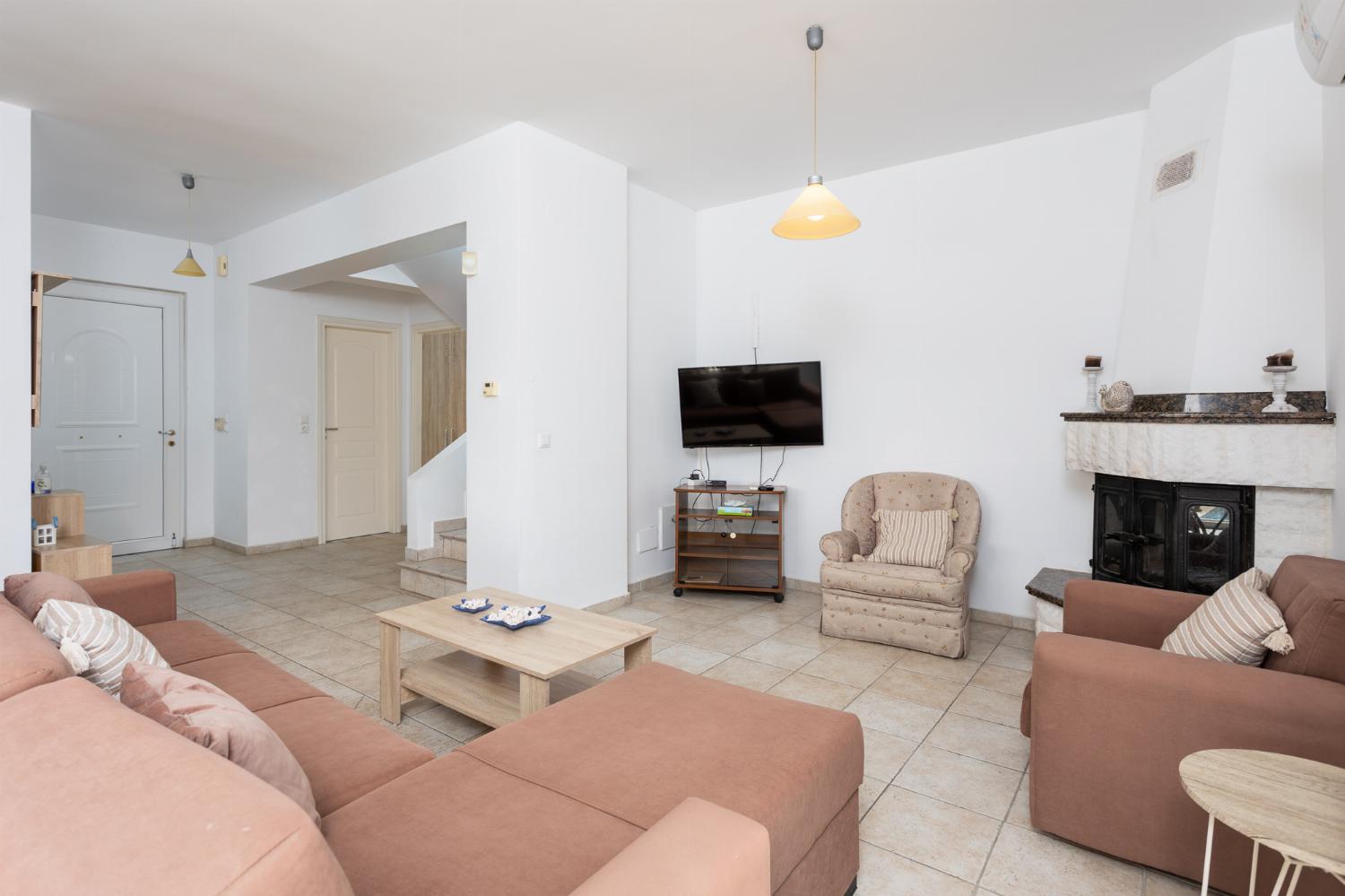 Open-plan living room with sofa, dining area, kitchen, ornamental fireplace, A/C, WiFi internet, and satellite TV