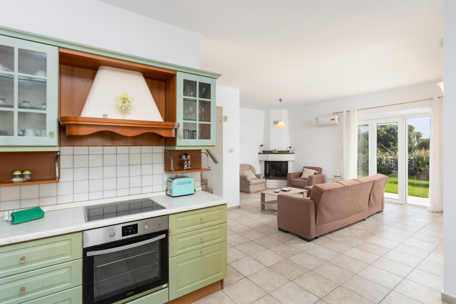 Open-plan living room with equipped kitchen, sofas, ornamental fireplace and terrace access
