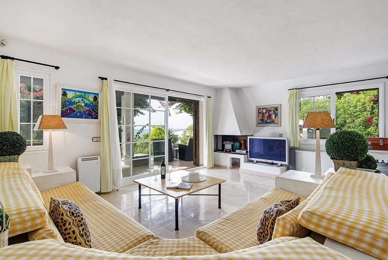 Open-plan living room with sofas, ornamental fireplace, dining area, kitchen, A/C, WiFi internet, satellite TV, DVD player, and pool terrace access