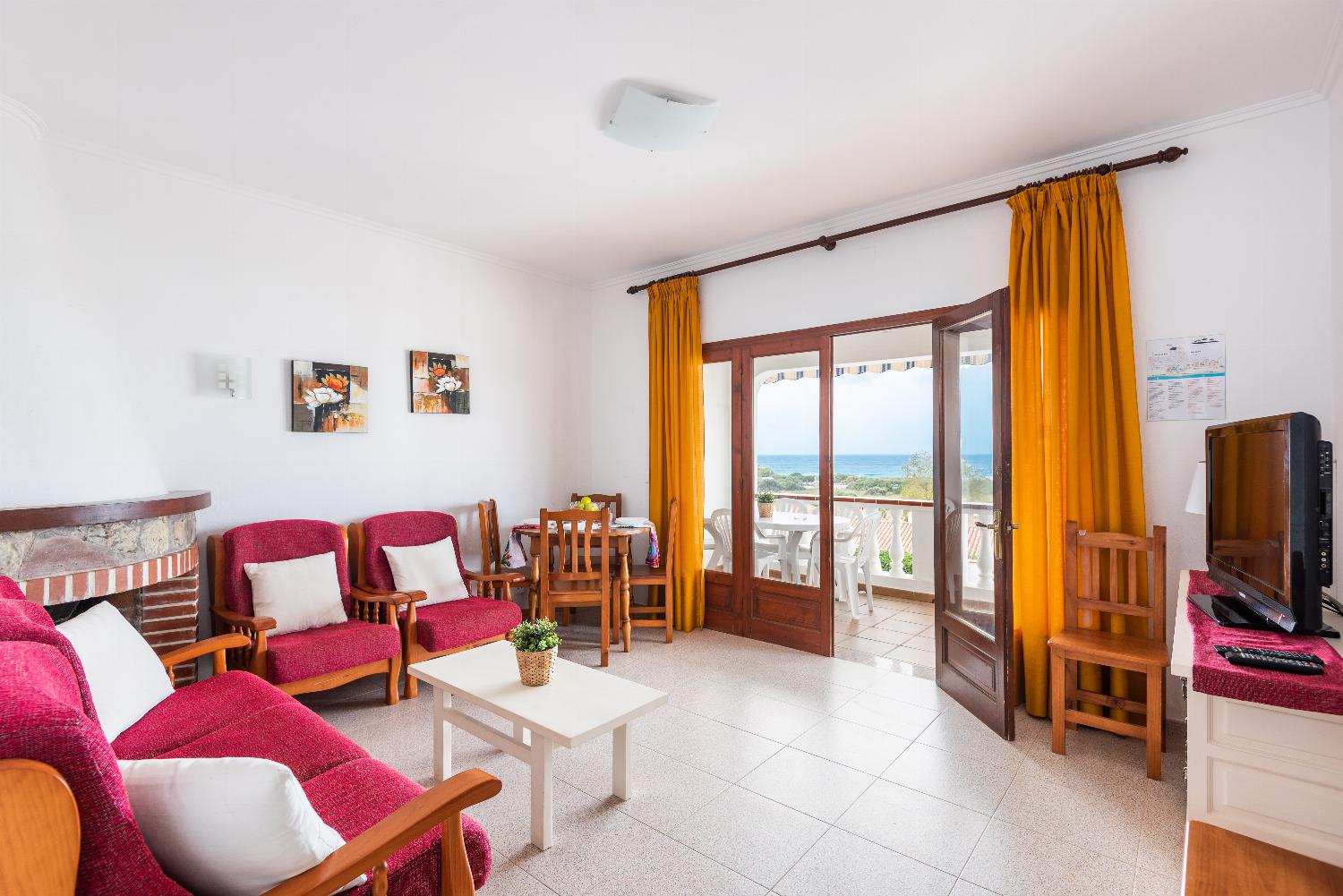 Open-plan living room with sofas, ornamental fireplace, dining area, kitchen, A/C, WiFi internet, satellite TV, DVD player, and pool terrace access
