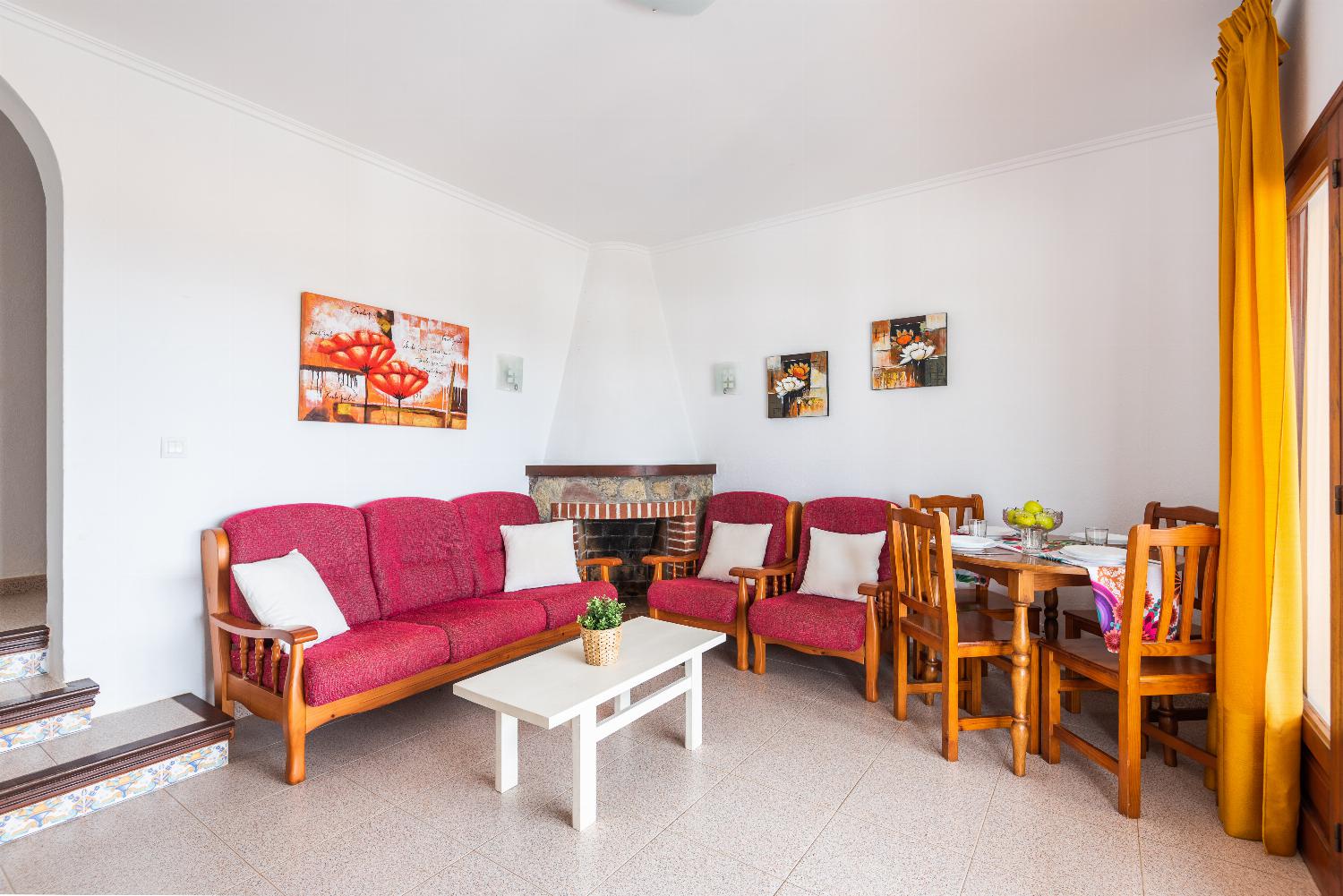 Open-plan living room with sofas, ornamental fireplace, dining area, kitchen, A/C, WiFi internet, satellite TV, DVD player, and pool terrace access