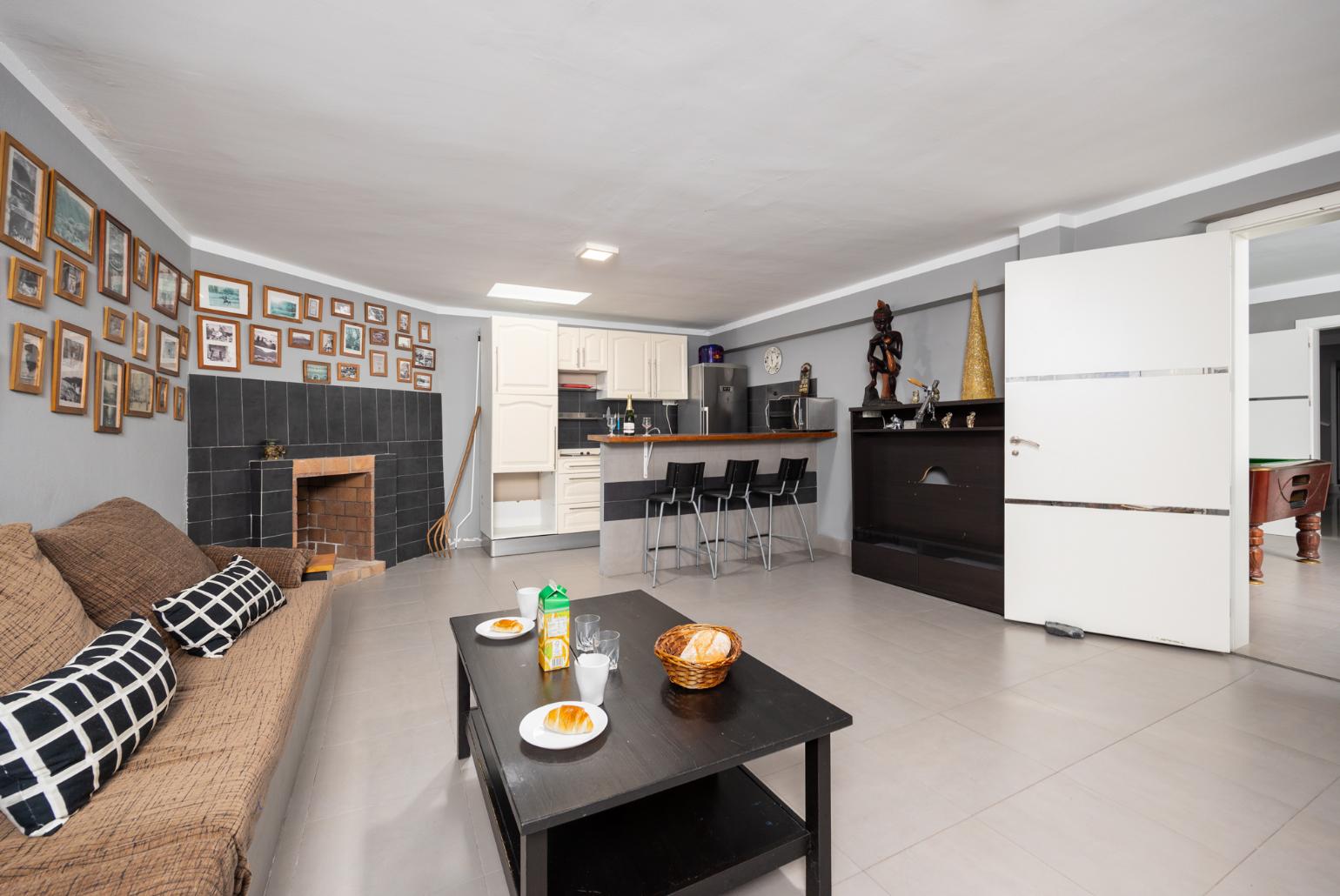 Living room with sofa, kitchen, and ornamental fireplace