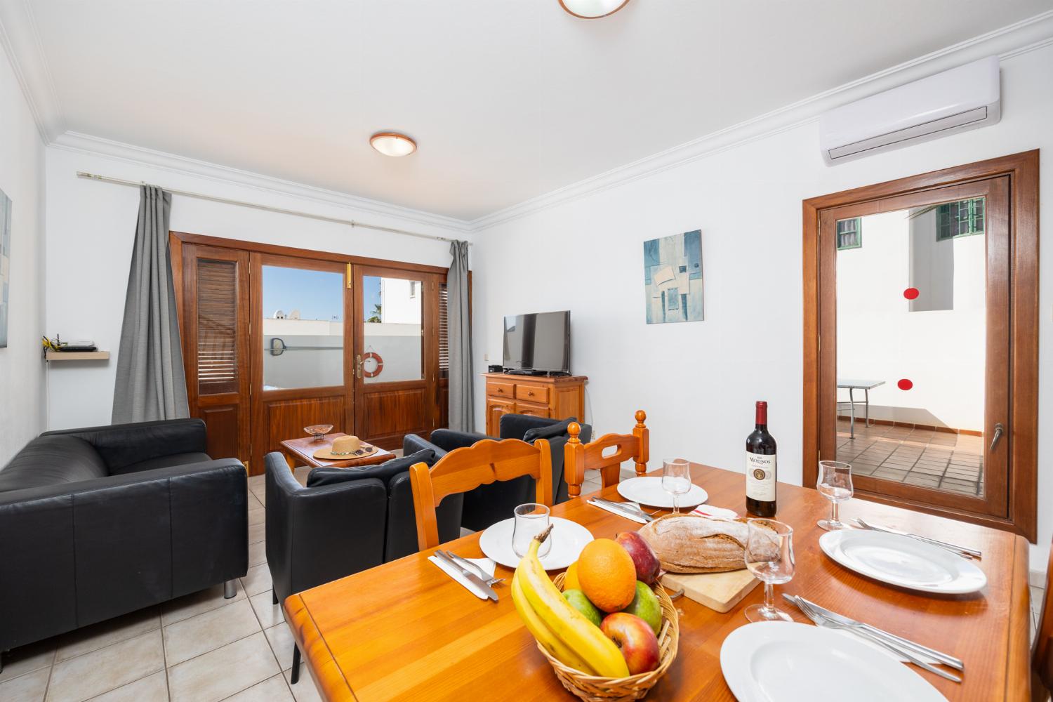 Living room with sofa, dining area, A/C, WiFi internet, and satellite TV