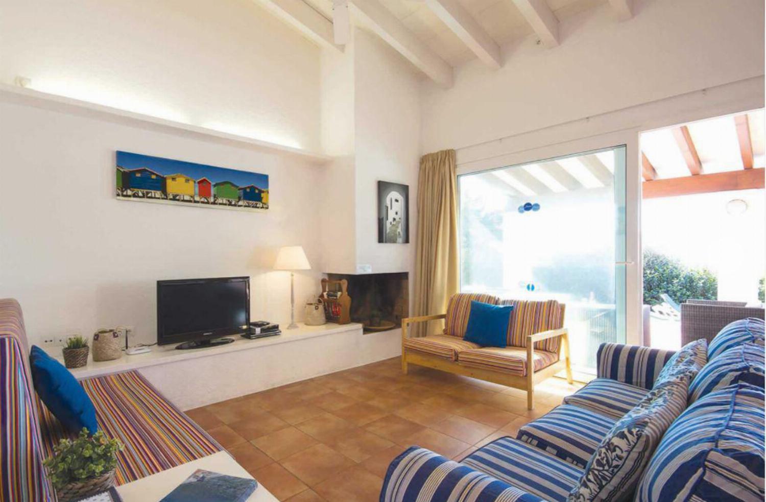 ,Open-plan living room with patio doors comfortable sofas TV, DVD, ornamental fireplace and dining area