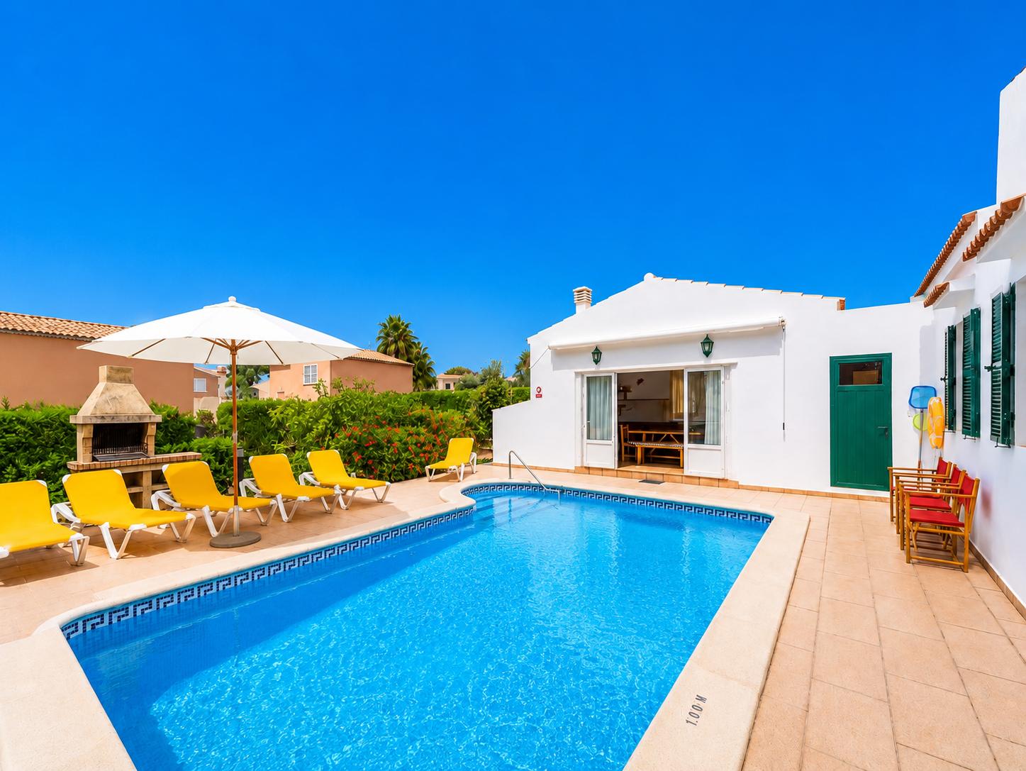 Sunny private pool area with yellow sun loungers, BBQ space, and a bright Mediterranean villa setting.