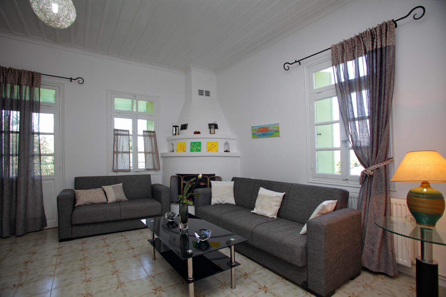 Open-plan living room with sofa, ornamental fireplace, dining area, kitchen, WiFi internet, satellite TV