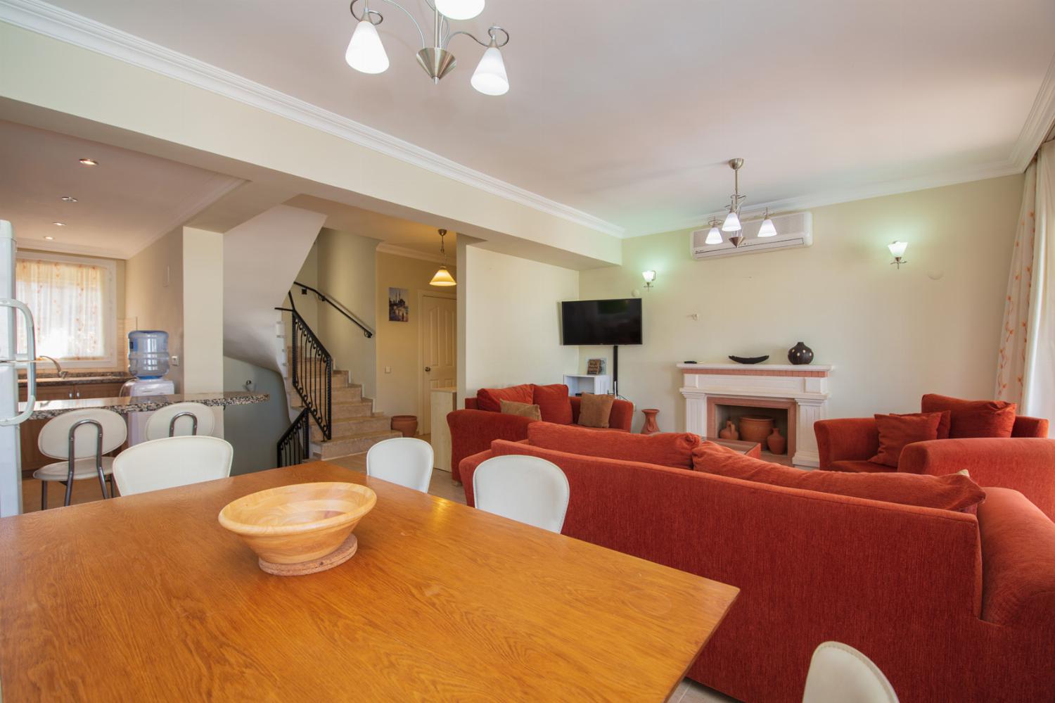 Open-plan living room with A/C, WiFi, TV, DVD, comfortable sofas, ornamental fireplace, dining area