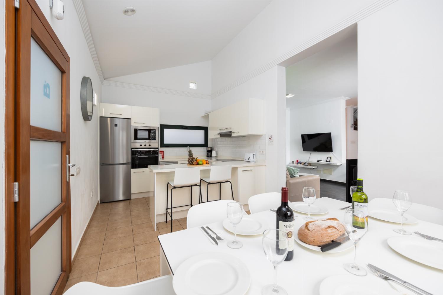 Open-plan living room with sofa, dining area, kitchen, ornamental fireplace, A/C, WiFi internet, and satellite TV