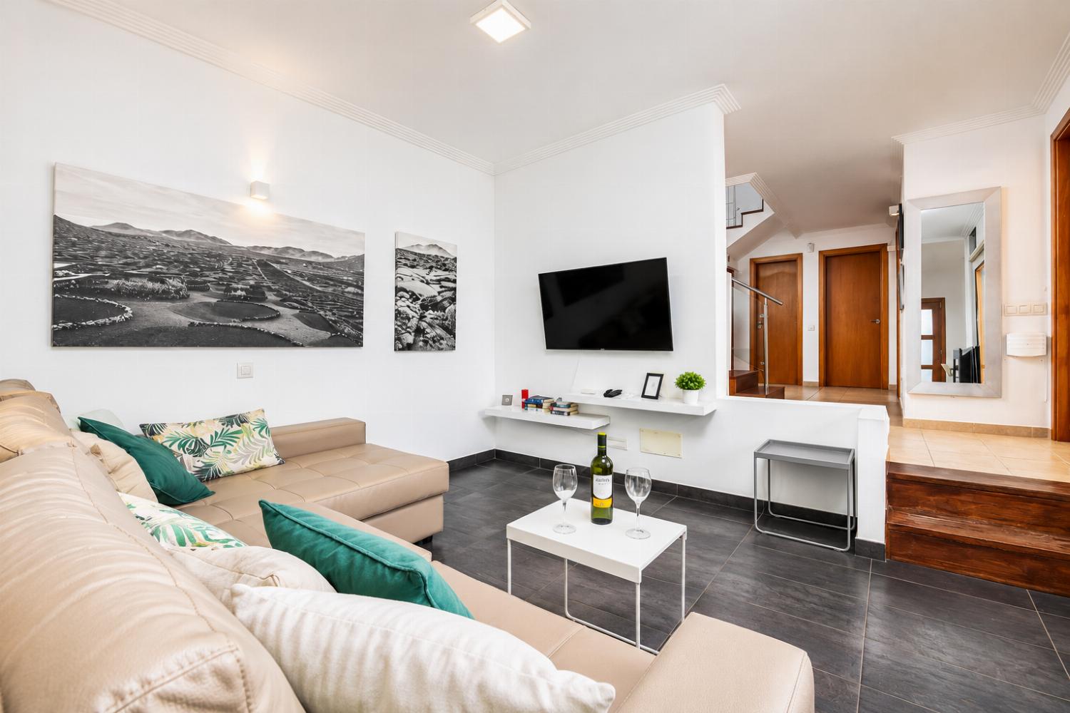 Open-plan living room with sofa, dining area, kitchen, ornamental fireplace, A/C, WiFi internet, and satellite TV