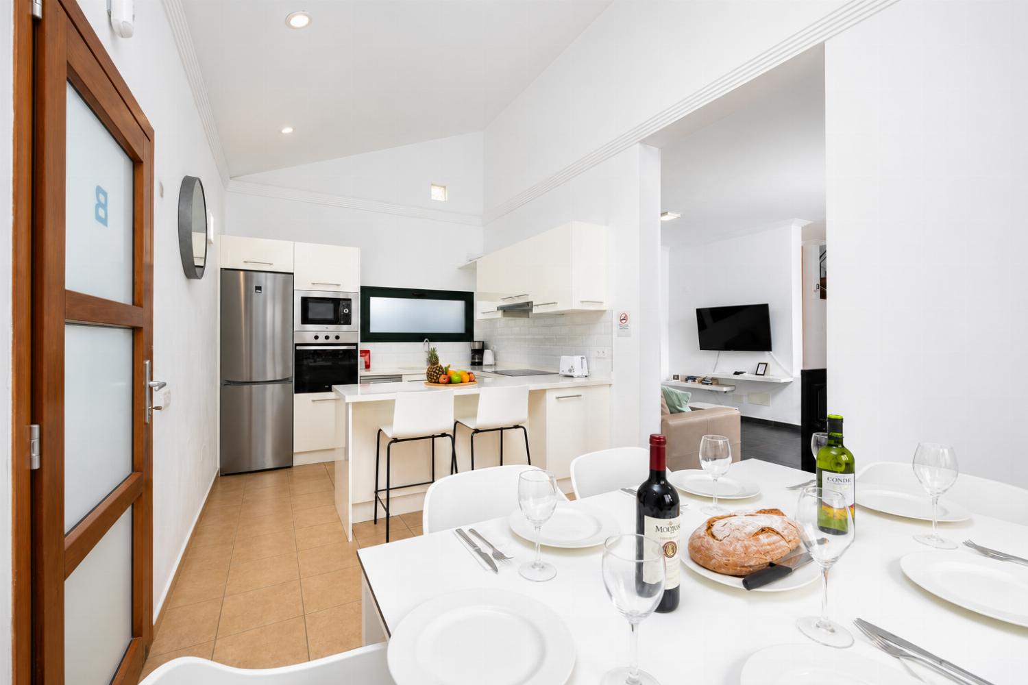 Open-plan living room with sofa, dining area, kitchen, ornamental fireplace, A/C, WiFi internet, and satellite TV