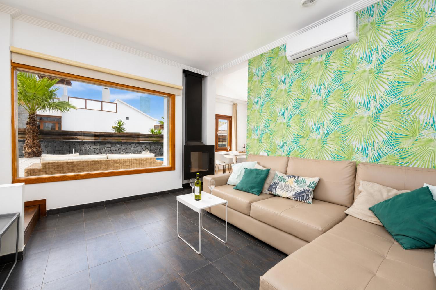 Open-plan living room with sofa, dining area, kitchen, ornamental fireplace, A/C, WiFi internet, and satellite TV