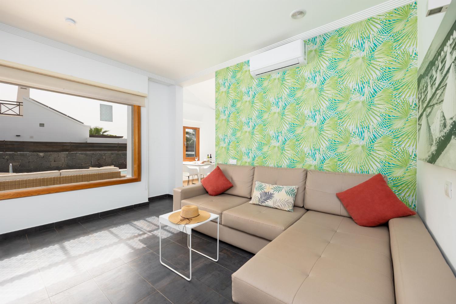 Open-plan living room with sofa, dining area, kitchen, A/C, WiFi internet, and satellite TV