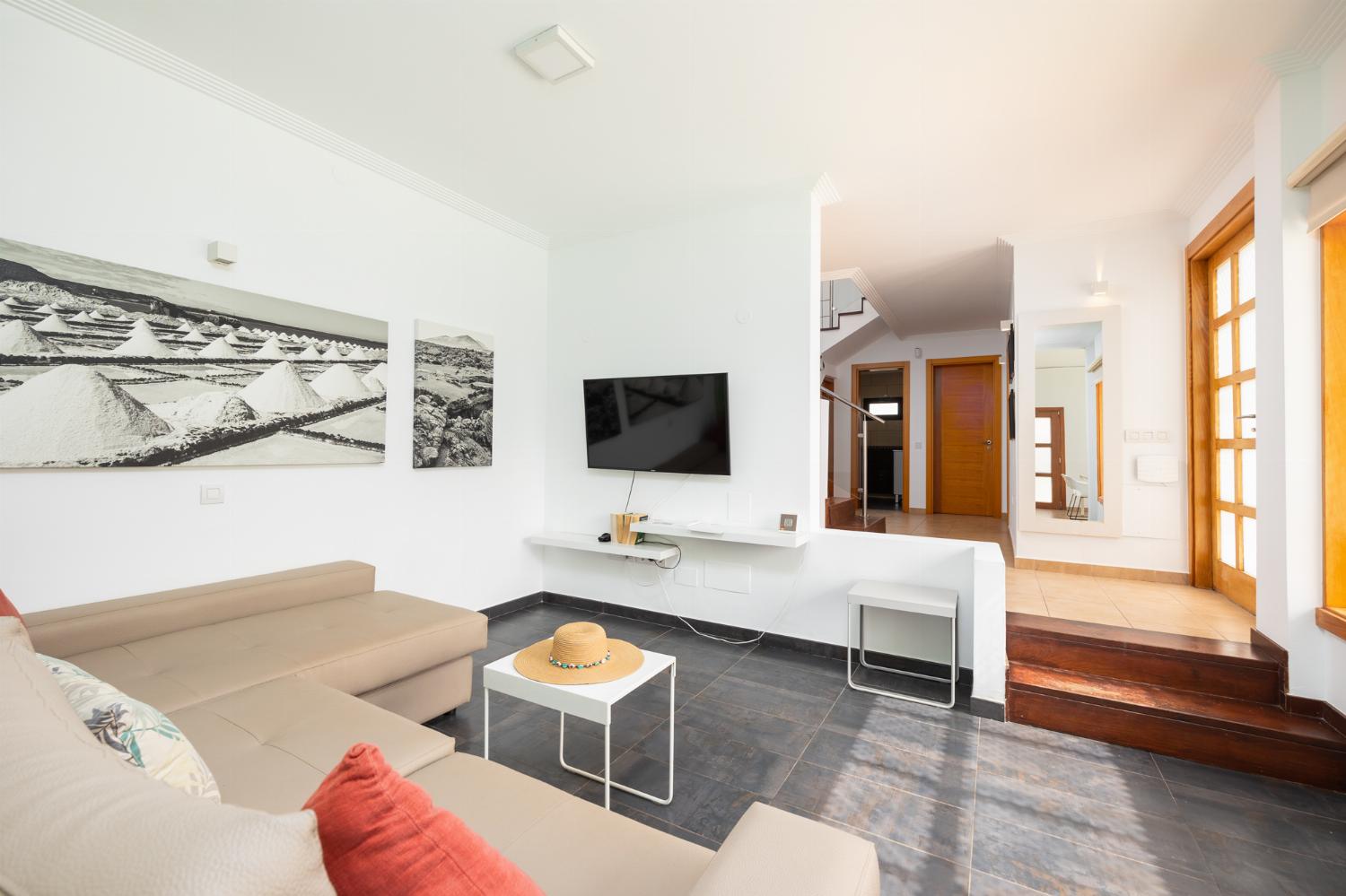 Open-plan living room with sofa, dining area, kitchen, A/C, WiFi internet, and satellite TV