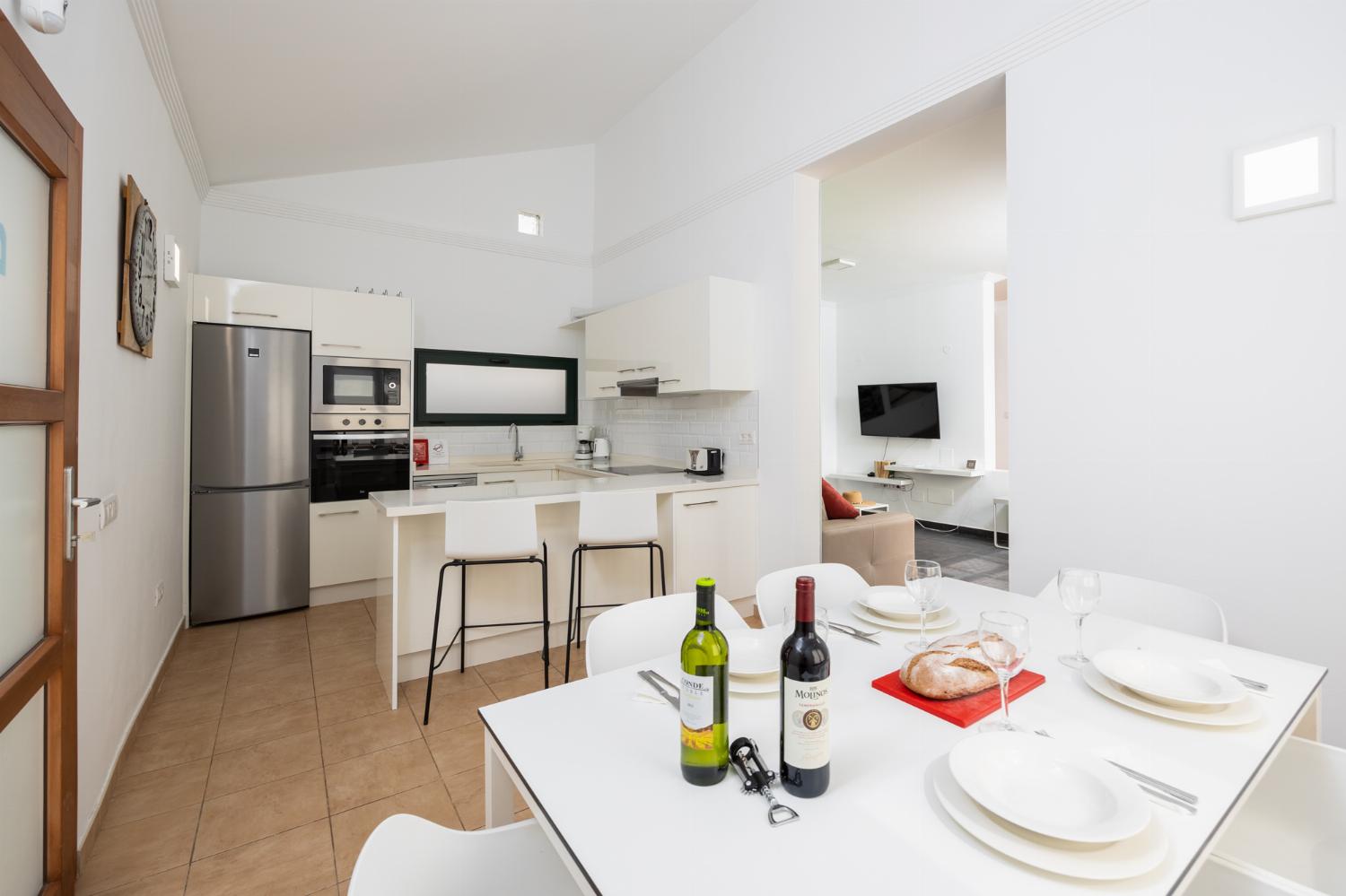 Open-plan living room with sofa, dining area, kitchen, A/C, WiFi internet, and satellite TV