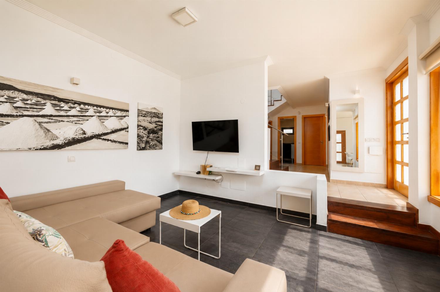 Open-plan living room with sofa, dining area, kitchen, A/C, WiFi internet, and satellite TV