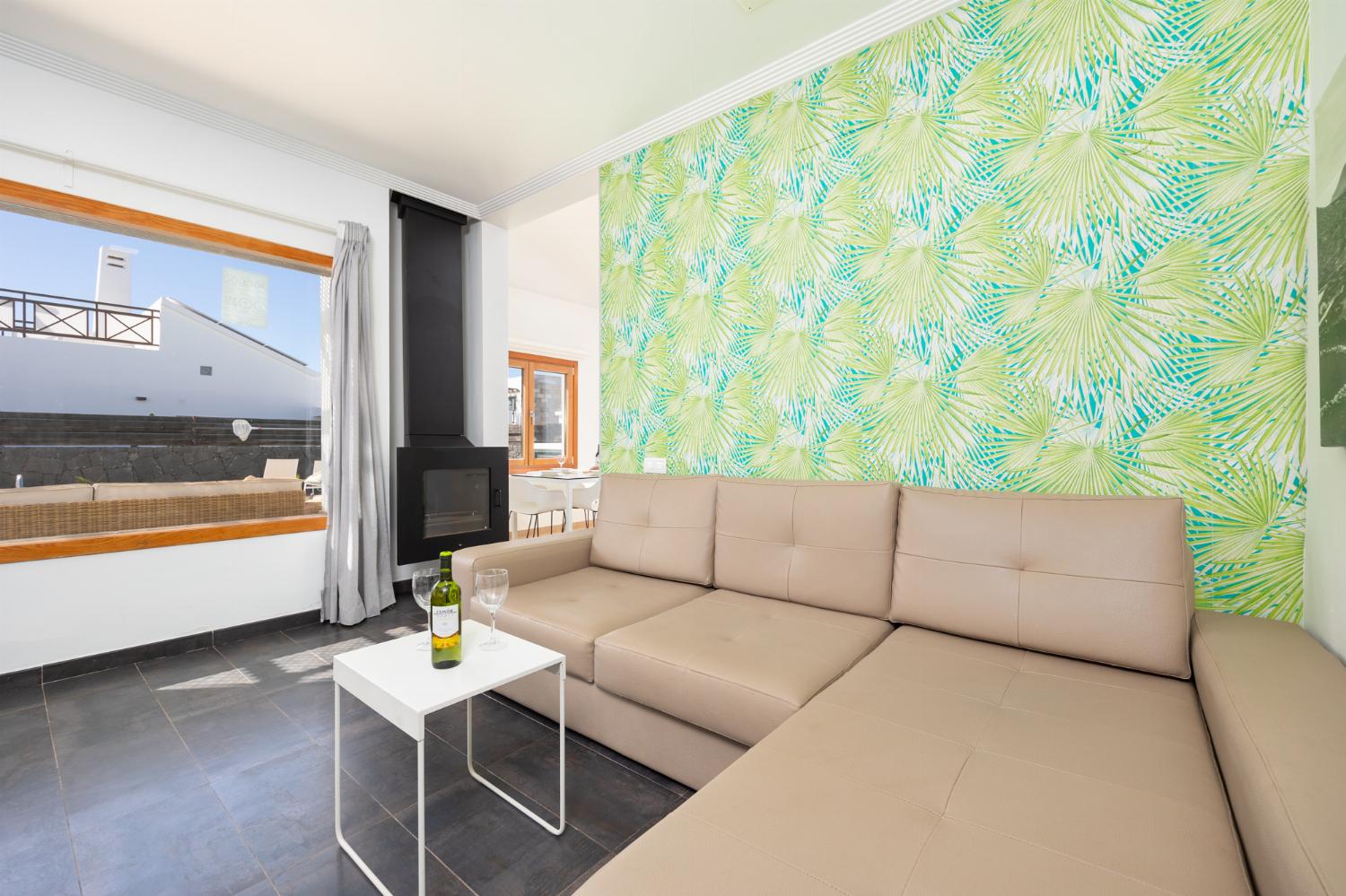 Open-plan living room with sofa, dining area, kitchen, ornamental fireplace, A/C, WiFi internet, and satellite TV