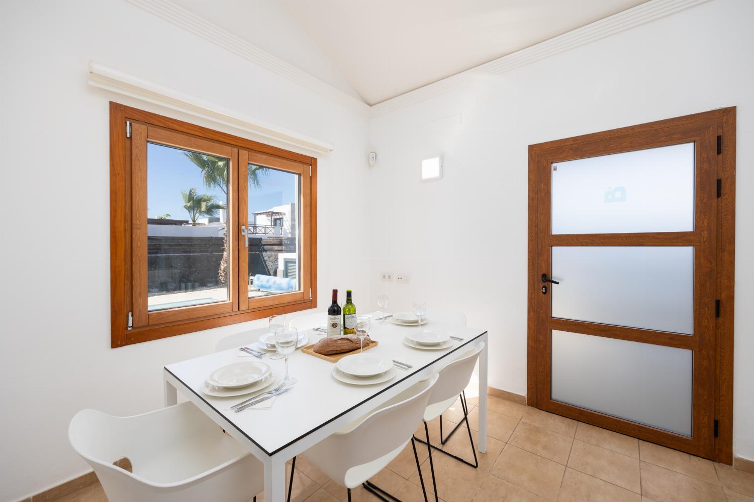 Open-plan living room with sofa, dining area, kitchen, ornamental fireplace, A/C, WiFi internet, and satellite TV
